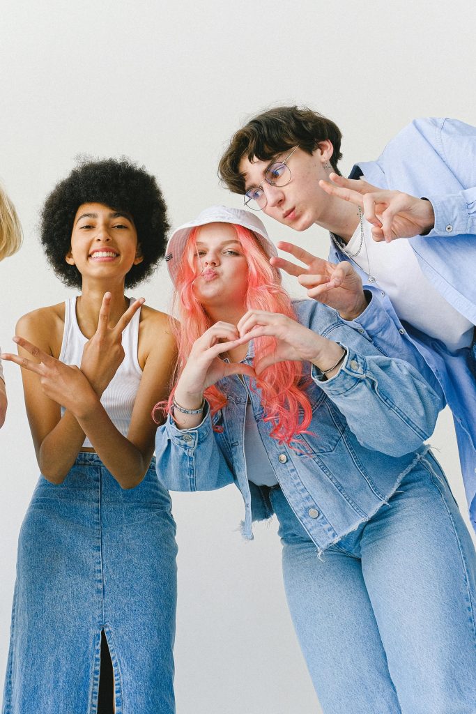 pexels-photo-5325708-5325708 Low angle of delighted teenager friends in denim wear looking at camera while making gestures and standing against white background